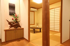 A traditional Japanese interior with tatami flooring, a low wooden table, and a decorative wooden piece on a cabinet. - Palm Villa Ishigakijima Igusa (Ishigaki)
