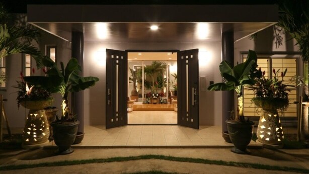 A modern building entrance with a wide doorway, potted plants on either side, and a well-lit interior visible through the open doors. - Palm Villa Ishigakijima Igusa (Ishigaki)