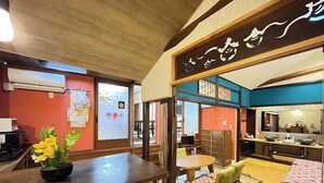 A traditional Japanese-style room with tatami flooring, a low table with cushions, and a bookshelf. - Guesthouse Wazakura (Sakurai)