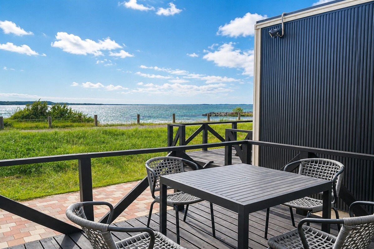 A deck with a table and chairs overlooking a body of water.