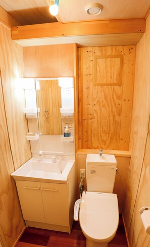 Une petite salle de bain en bois, équipée d’un lavabo, de toilettes et d’un miroir.