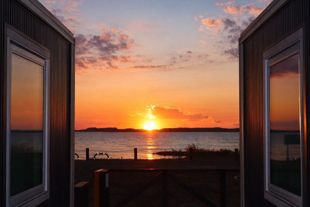 A sunset view from a balcony with a railing and a wooden deck.