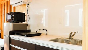 A compact kitchen with a microwave, stove, and sink. - Kasumi Terrace Kasumigaura (Namegata)