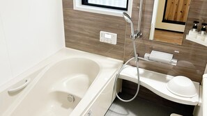 Un baño moderno con bañera, inodoro, ducha de mano y panel de control.
