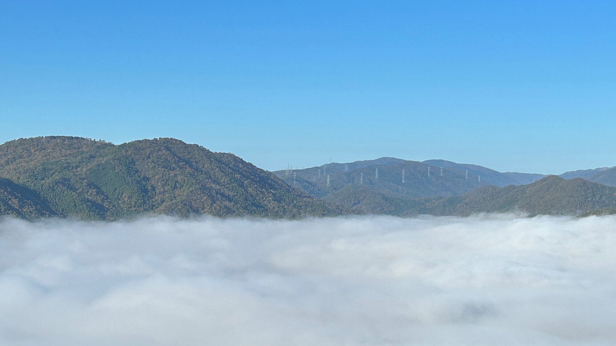 Paesaggio montuoso con uno strato di nuvole alla base.
