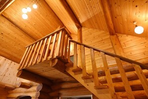Una escalera de madera con barandilla de metal que conduce a una zona superior.