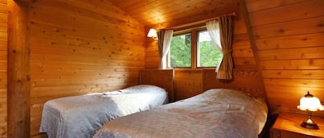 Une cabine avec deux lits, une fenêtre avec des rideaux et une lampe sur une table de chevet.