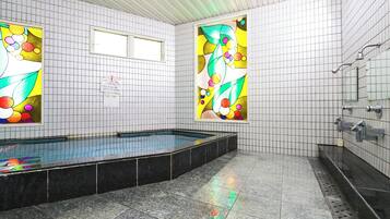 A swimming pool with tiled walls and a tiled floor, surrounded by a tiled area with a bench.