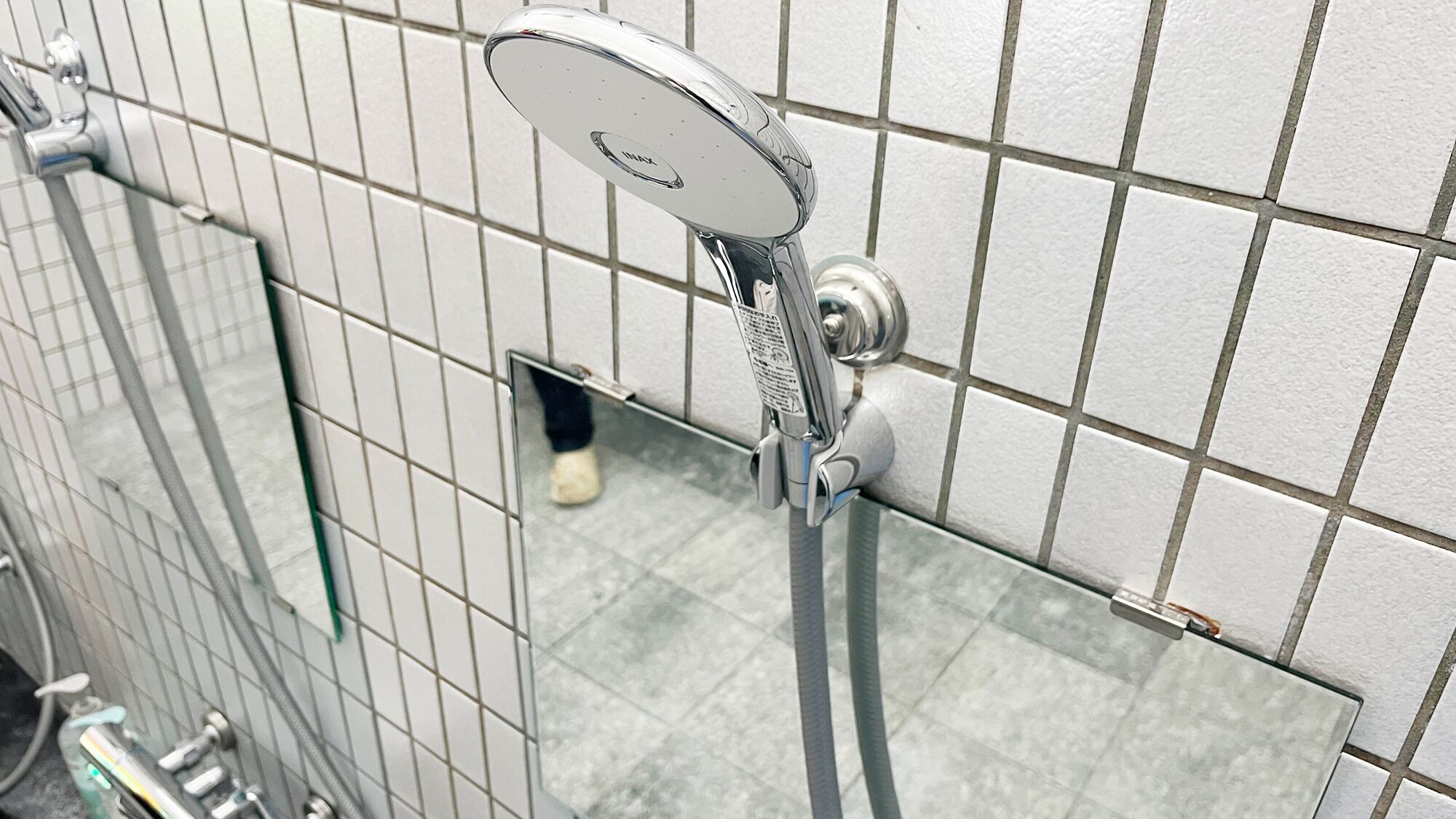 A shower with a handheld showerhead and a wall-mounted control panel.