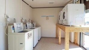 A laundry room with multiple washing machines, a wooden table, and a wall-mounted sign. - Tochigi Grand Hotel (Tochigi)