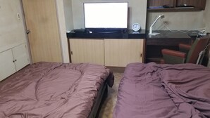 Un dormitorio con dos camas, un escritorio con computadora, una silla y un reloj en la pared.