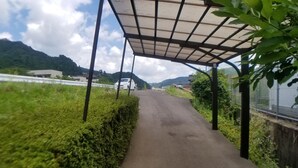 Un sendero conduce a una zona cubierta con vistas a una montaña y un edificio en la distancia.