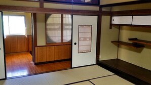 Una habitación japonesa tradicional con suelo de tatami, puertas correderas y una estantería de madera.