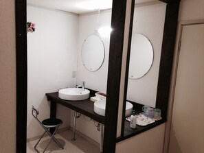 A bathroom with two sinks, a mirror, and a small stool.