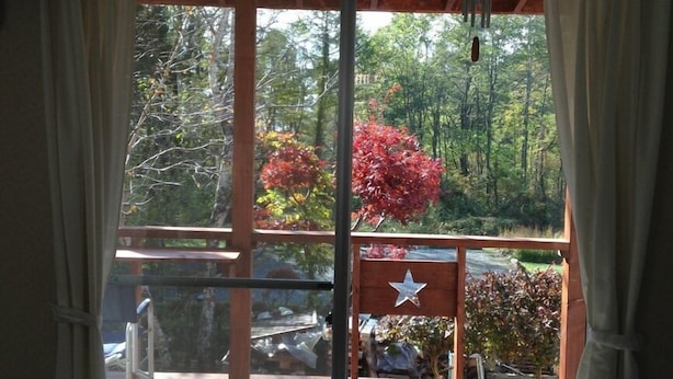 A room with a sliding glass door leading to an outdoor deck with a star decoration, wooden furniture, and a potted plant.