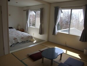 A room with a bed, a small table, and a window with curtains.