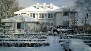 A snow-covered house with a garage, a car, and a snow-covered driveway.