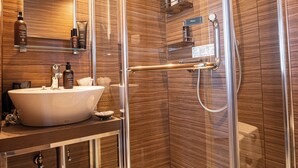 Ein modernes Badezimmer mit einer gläsernen Duschkabine, einem Waschtisch und einem Spiegel.