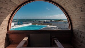 Une cabane en bois avec une piscine et vue sur l’océan.
