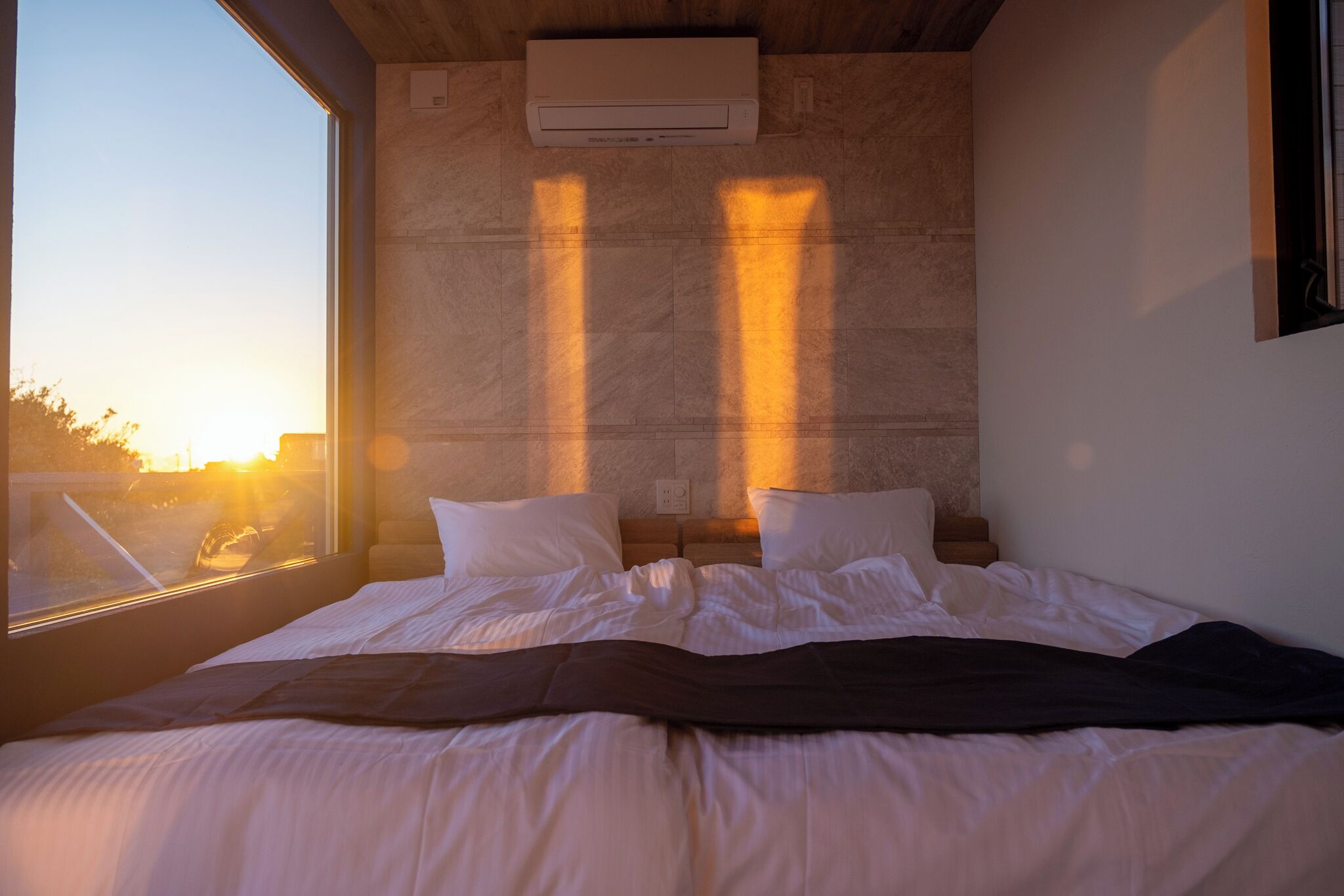 Une chambre à coucher avec un grand lit, une fenêtre et un climatiseur mural.