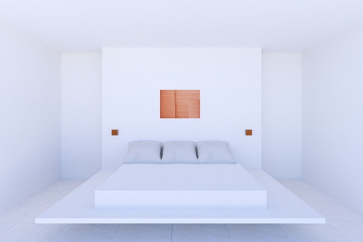 A minimalist bedroom with a single bed, white walls, and a small wooden panel above the bed.
