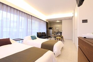 Une chambre d’hôtel avec deux lits, un bureau, une chaise et un téléviseur.