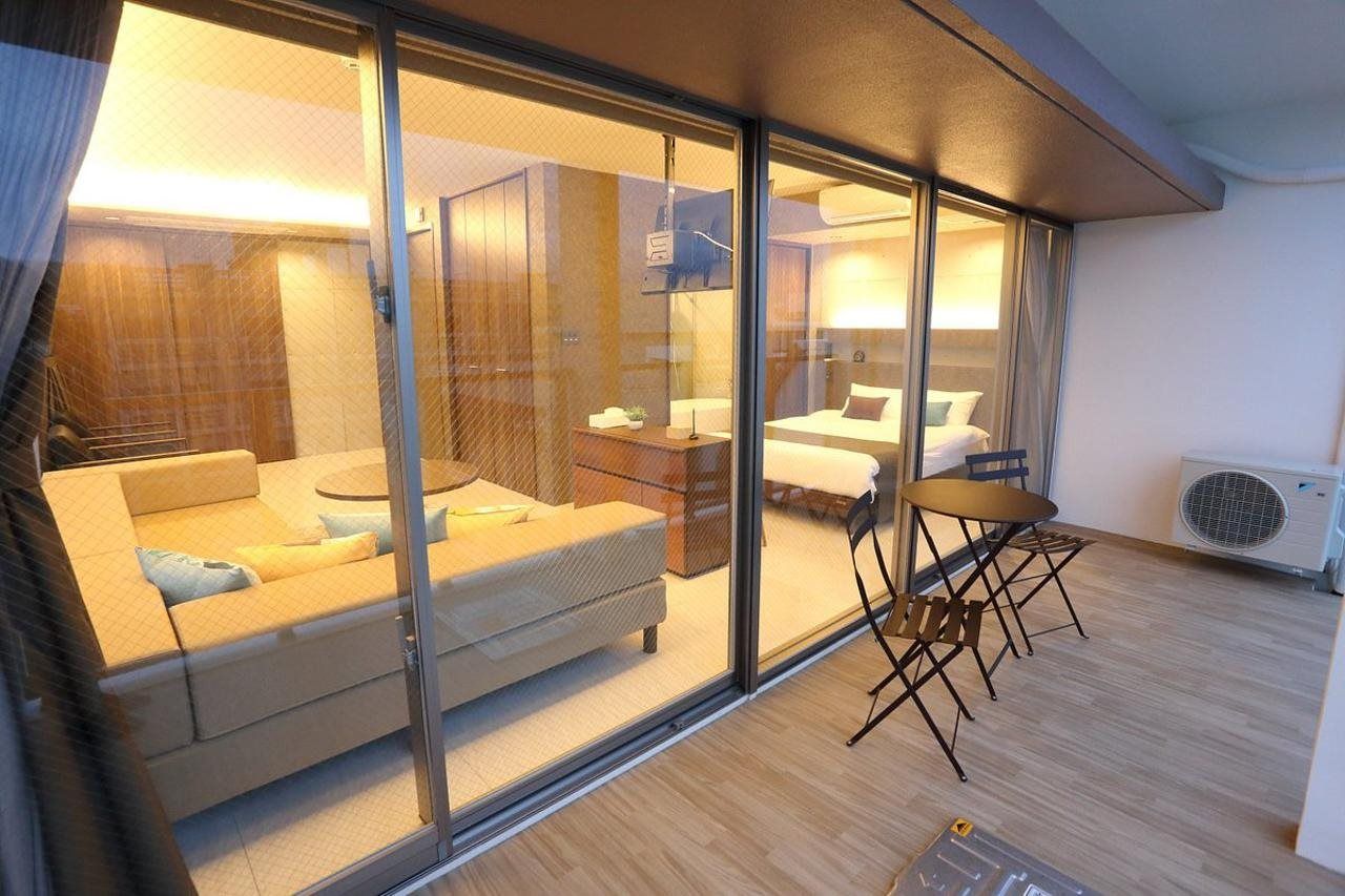 Una habitación de hotel moderna con un separador de vidrio, un sofá, una mesita y una cama.