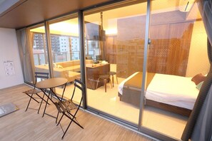 A hotel room with a bed, a desk, and a seating area with a table and chairs. - Tabinoteitaku Okinawa Naha (Naha)