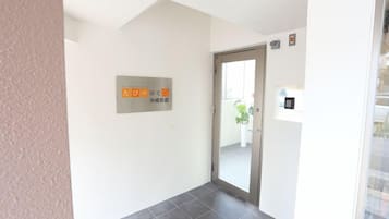 A hotel entrance with a sign indicating the location, a door, and a keypad lock.