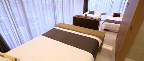 A hotel room with a bed, a bedside table, a TV, and a window with curtains.