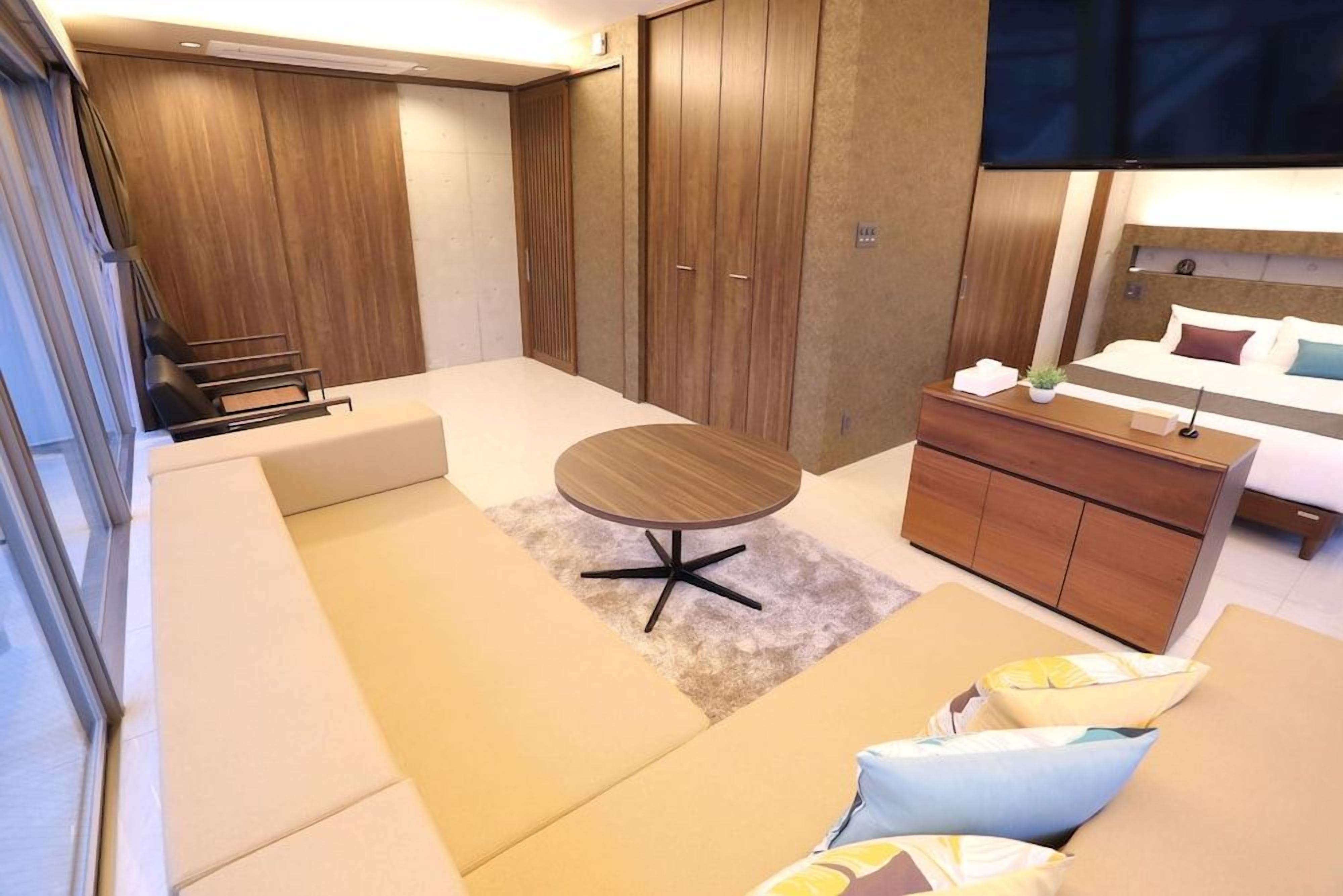 A modern hotel room with a bed, a small table, a sofa, and a wardrobe.