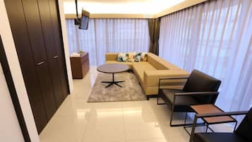 A modern living room with a sofa, a coffee table, and a TV mounted on the wall.