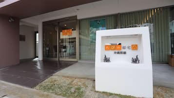 A modern building entrance with a reception desk, glass doors, and a small outdoor display with signage.