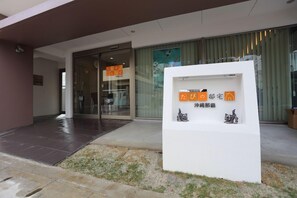 Une entrée moderne avec un comptoir d’accueil, des portes vitrées et un petit présentoir extérieur agrémenté de panneaux d’affichage.