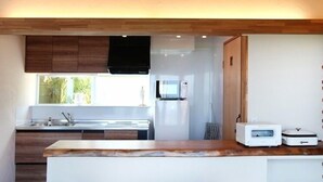 A modern kitchen with wooden cabinets, a built-in microwave, and a large window.