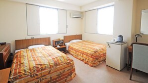 Habitación de hotel con dos camas, una kitchenette pequeña, un escritorio y un espejo.