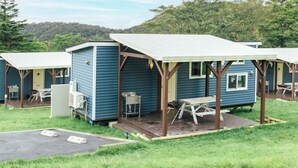 A row of small, blue mobile homes with attached porches and outdoor seating areas. - Pica Fuji Grinpa (Susono)
