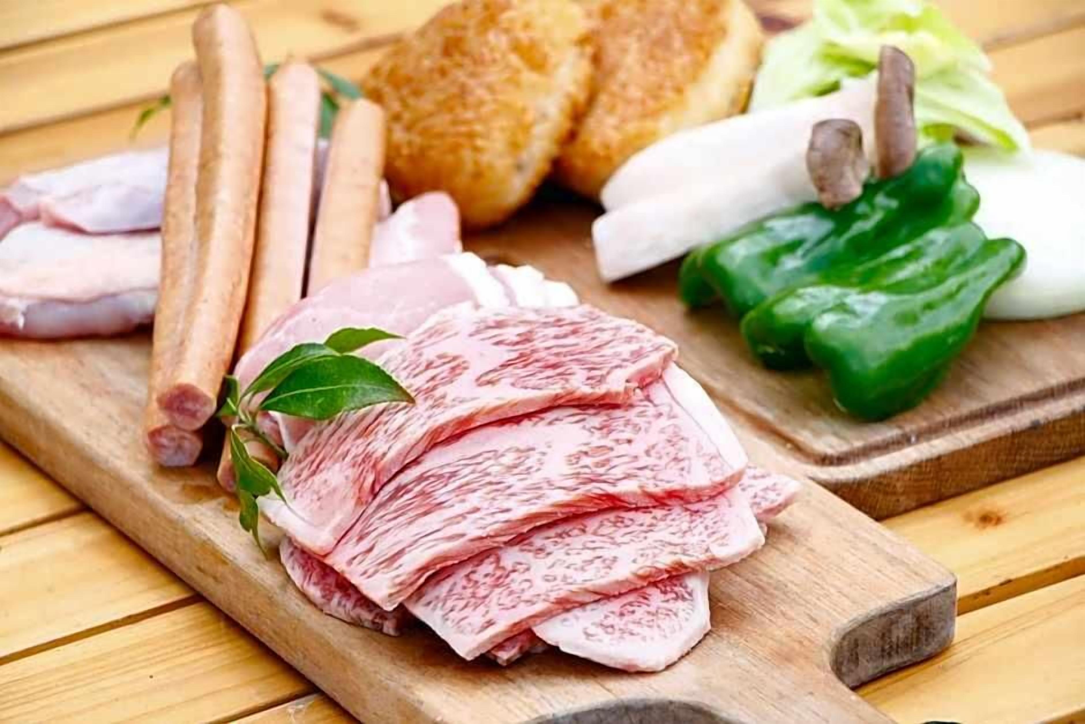 A wooden cutting board with sliced meat, bread, and vegetables.