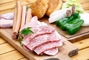 Una tabla de madera con carne en rodajas, pan y verduras.