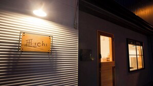 A hotel sign with the name "Hachi Life Style Hotel" mounted on a corrugated metal wall. - Life Style Hotel Ichi (Kochi)