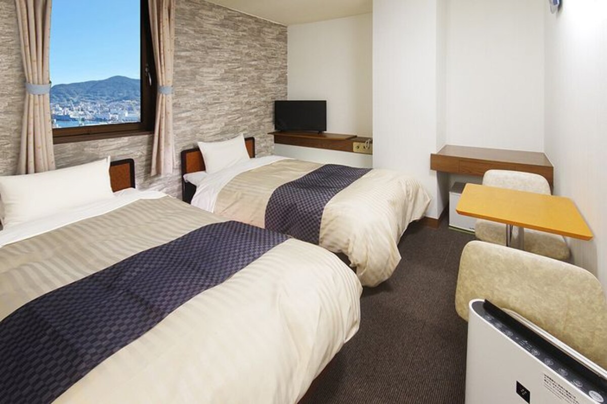 Une chambre d’hôtel avec deux lits, une télévision, un bureau et une chaise.