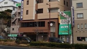 A multi-story hotel with a beige facade, several balconies, and a visible sign indicating a business or service on the ground floor. - Sasebo Daiichi Hotel (Sasebo)