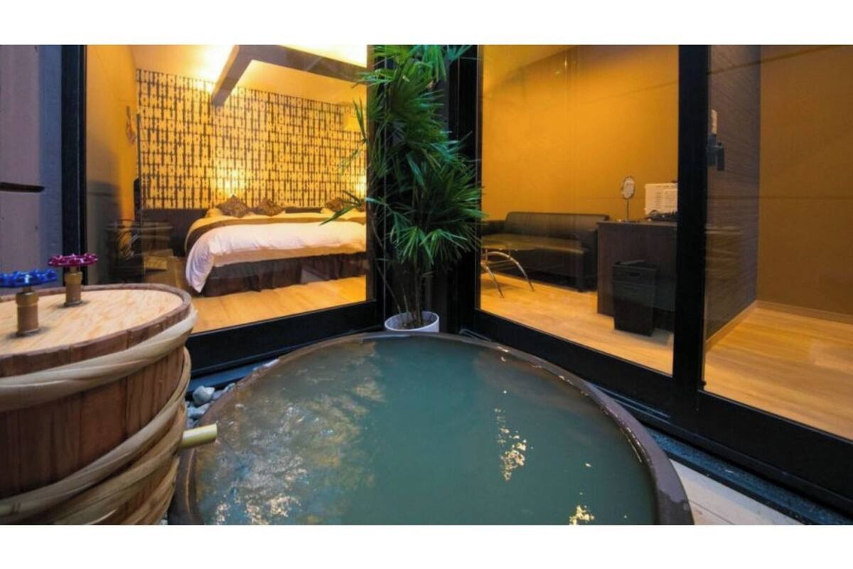 A spa room with a hot tub, a bed, and a large window.