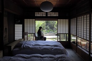 Ein traditioneller japanischer Raum mit Tatami-Bodenbelag, einem niedrigen hölzernen Bett und verschiebbaren Shoji-Bildschirmen.