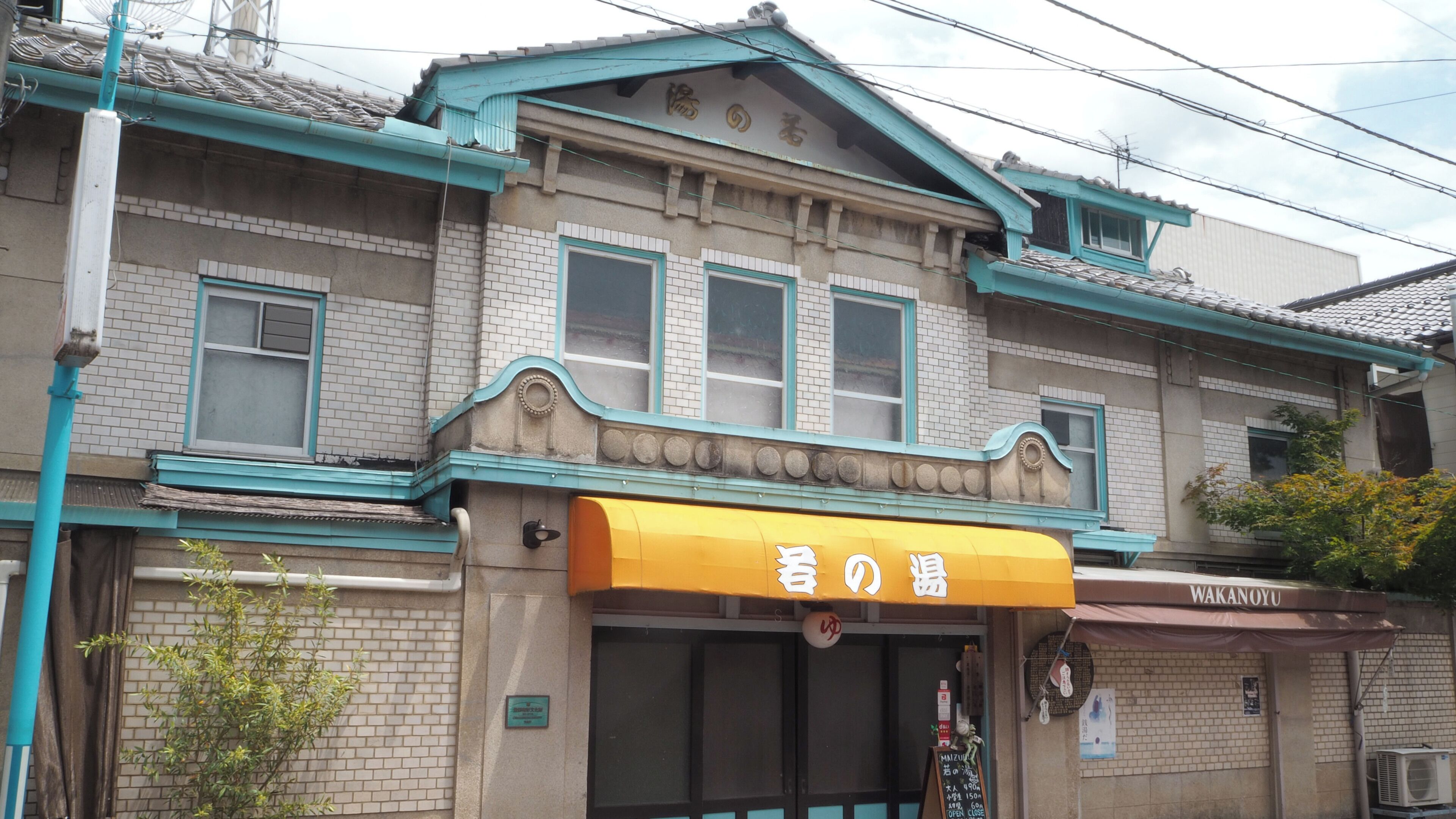 A traditional building with a yellow awning, a brick facade, and a tiled roof.