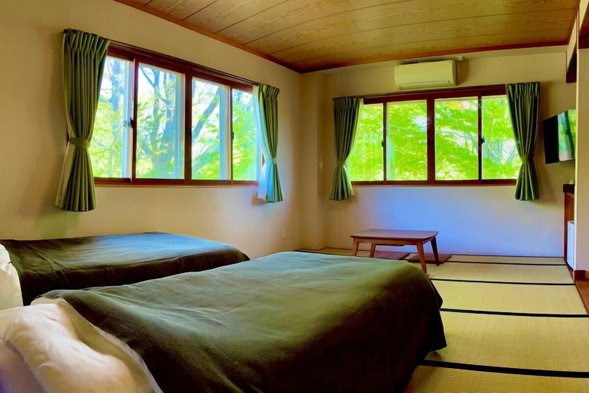 A room with two beds, a small table, and a television.