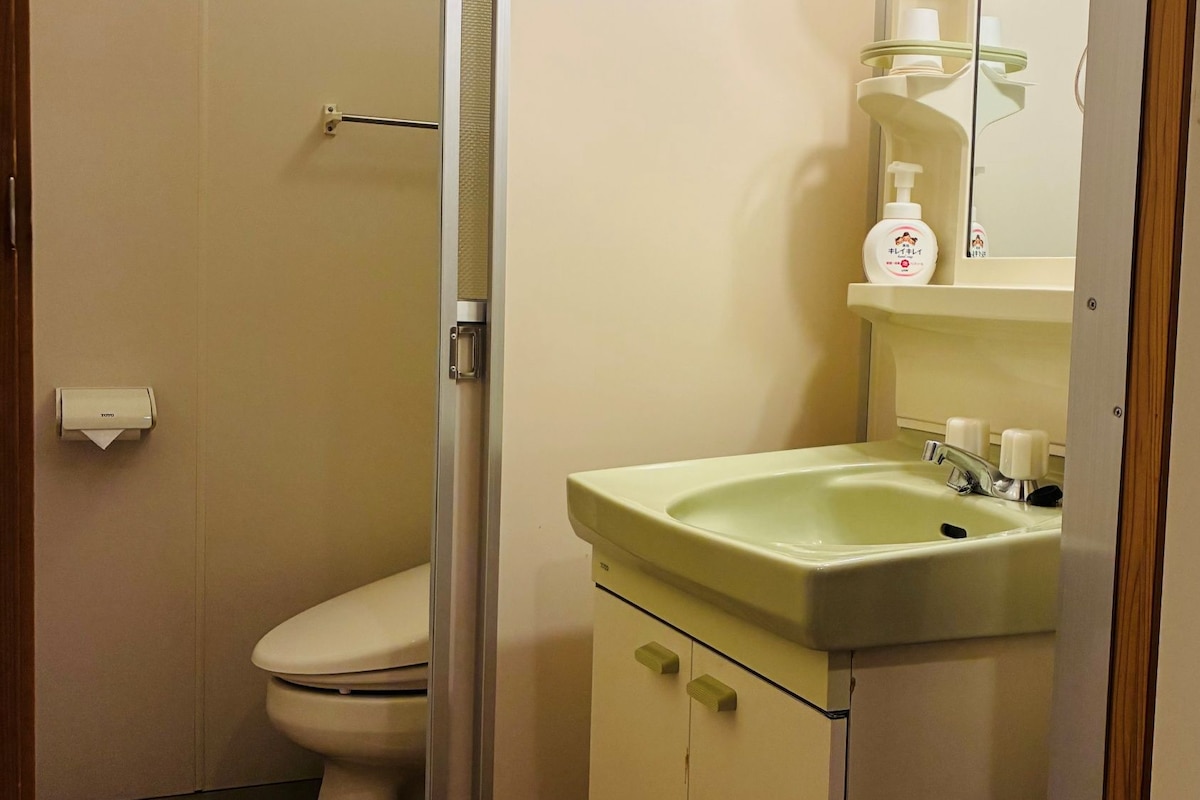 A bathroom with a toilet, a sink, and a mirror.