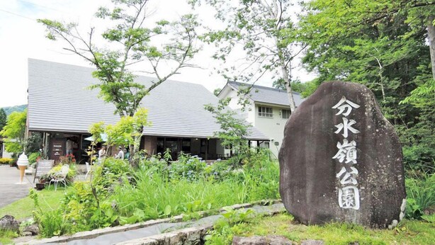 A stone with Japanese characters, a building with a grey roof, and a garden with various plants. - Tabi-yado Bunsuirei (Gujo)