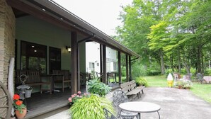 An outdoor patio area with wooden benches and tables, surrounded by greenery and trees. - Tabi-yado Bunsuirei (Gujo)