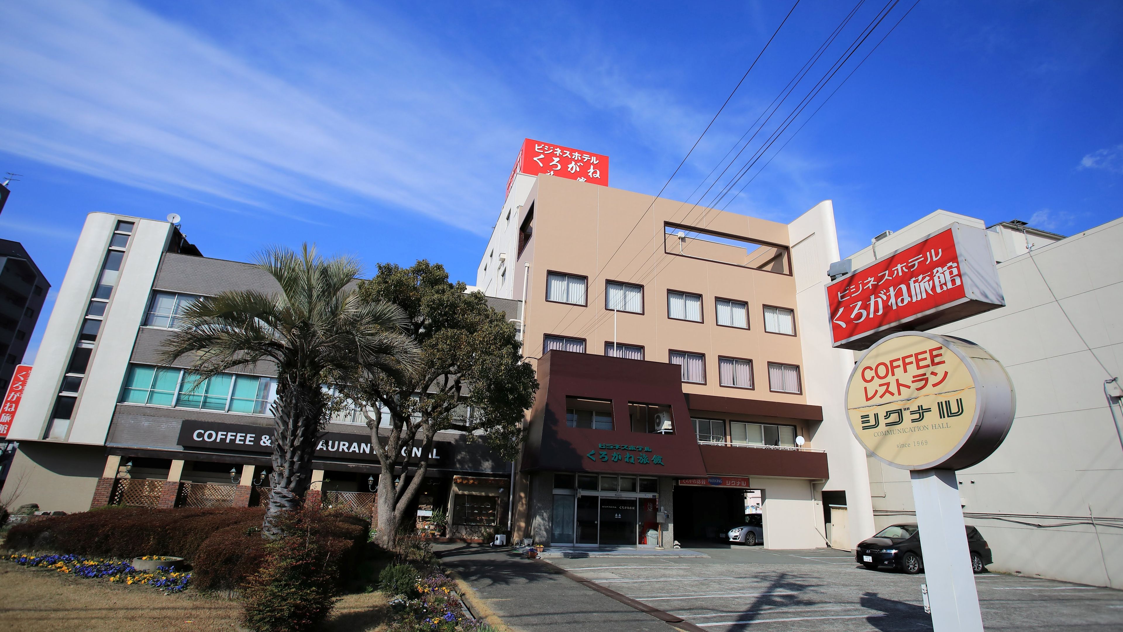 Un edificio con varios letreros que señalan un hotel, una cafetería y un salón de comunicaciones.